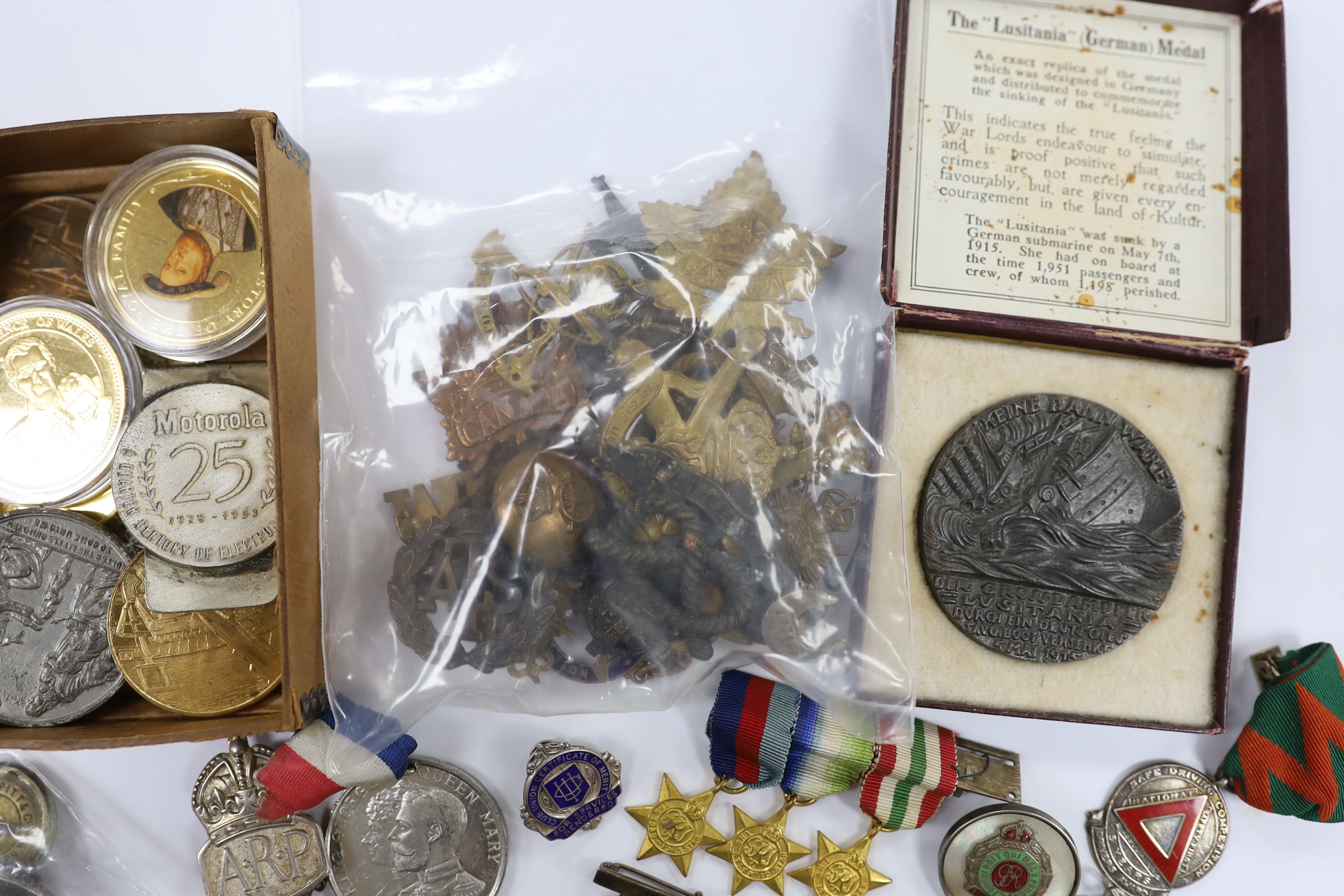 A collection of medals, cap badges, commemorative coins etc. including; a cased RMS Lusitania medal, Royal Artillery sweetheart brooches, a miniature WWII medal group of three stars; the 1939-45 Star, the Atlantic Star a
